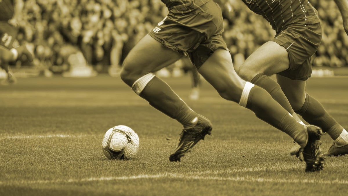 Två spelare tävlar om bollen i en fotbollsmatch.