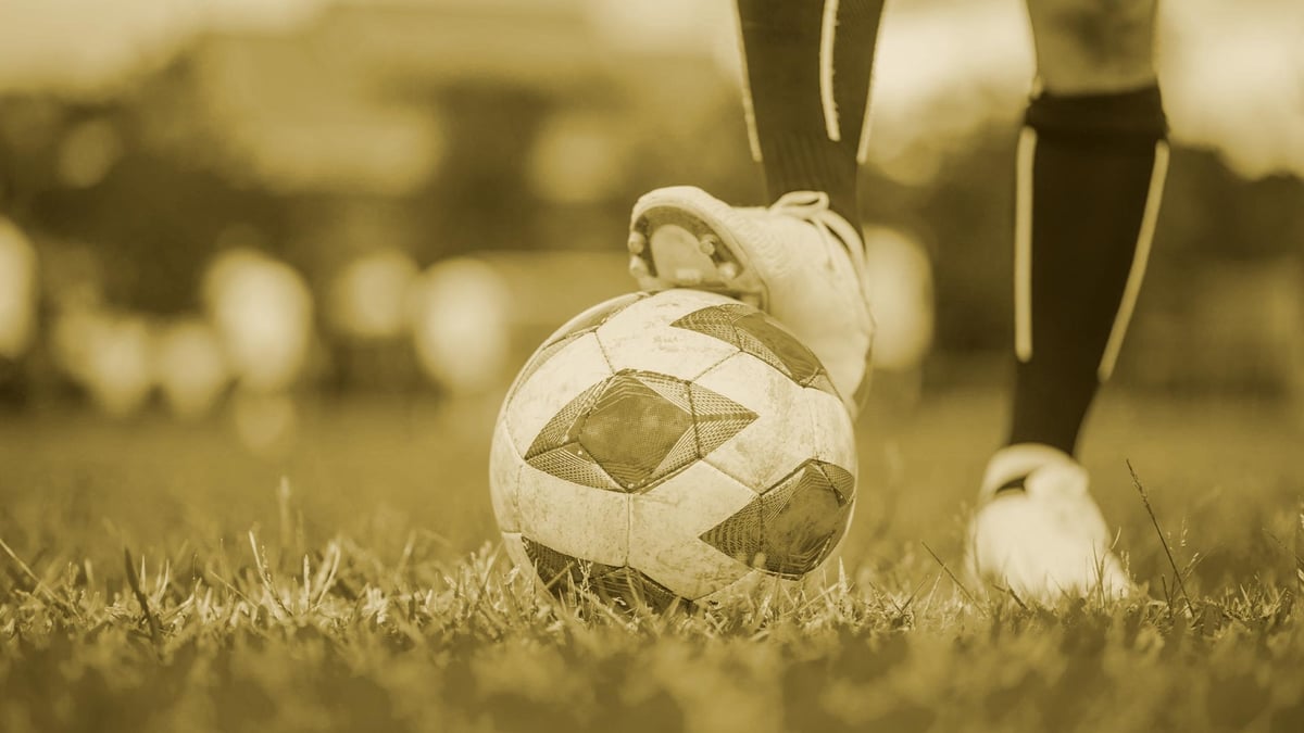 En spelare i Allsvenskan står med ena foton på en fotboll.