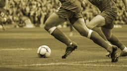 Två spelare tävlar om bollen i en fotbollsmatch.